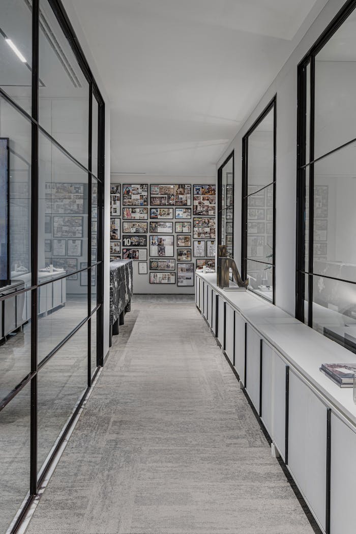 Sleek office hallway with glass walls and framed pictures. Ideal for corporate settings.
